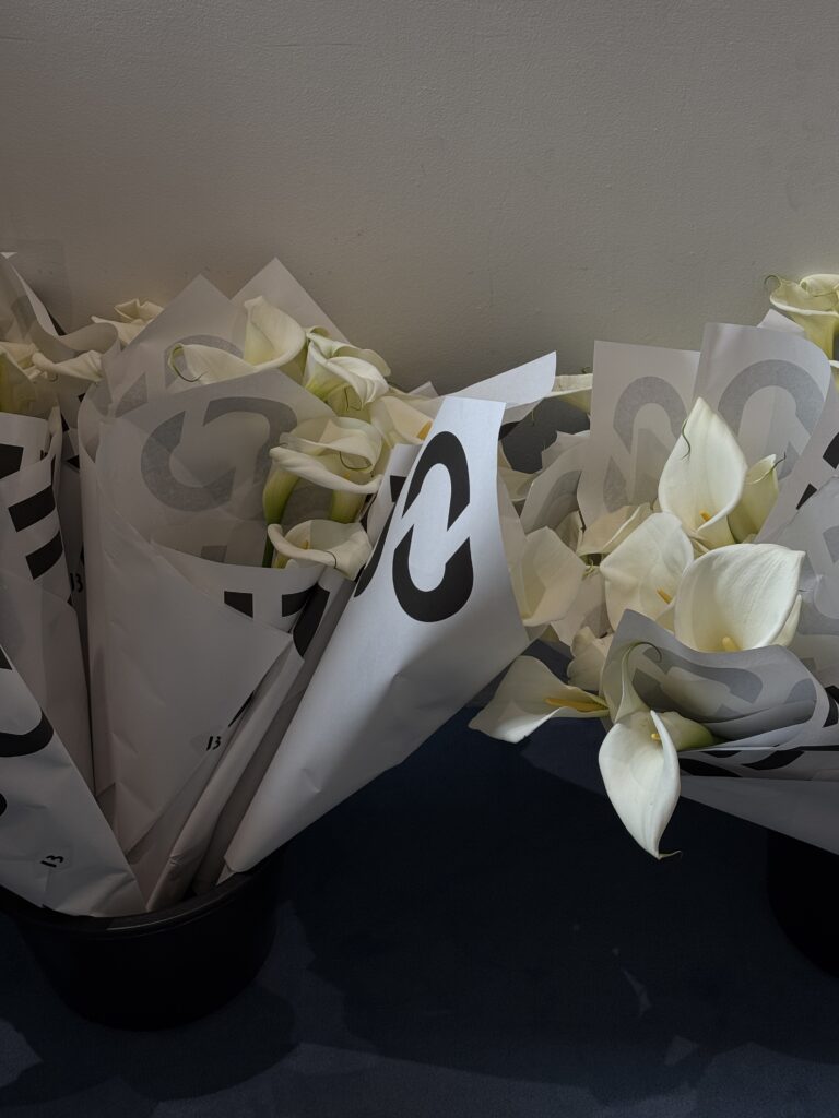 Mehrere Blumensträuße mit weißen Calla-Lilien, kunstvoll in Papier mit schwarzer BYREDO-Grafik verpackt.