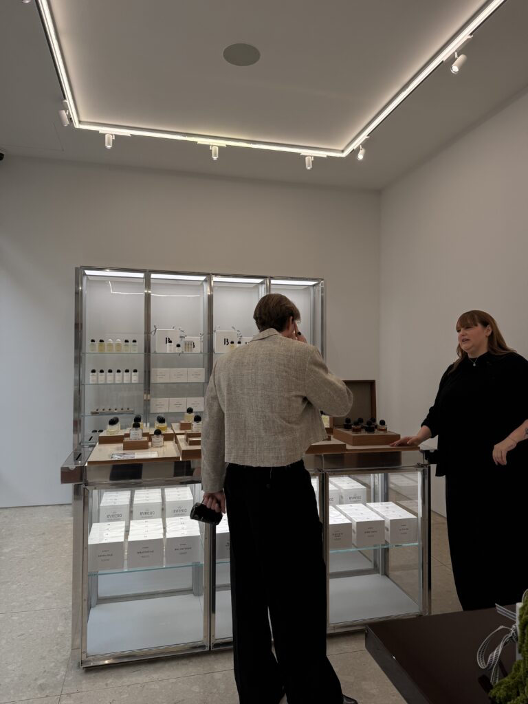 Kundenszene im BYREDO-Store mit Fokus auf Parfumtheke und Beratungssituation zwischen zwei Personen.